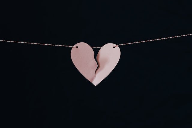 Corazón de papel rozado partido colgado en una cuerda