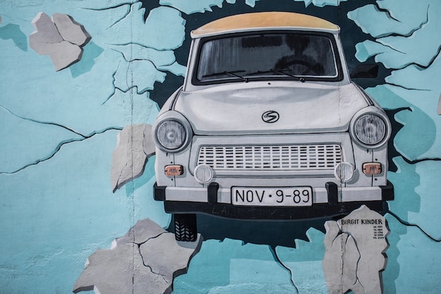 Foto de un mural del muro de berlín en que aparece un auto tipico de la DDR