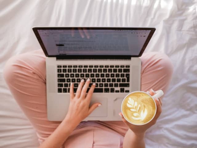 Persona tomando un café y viendo las noticias en su laptop