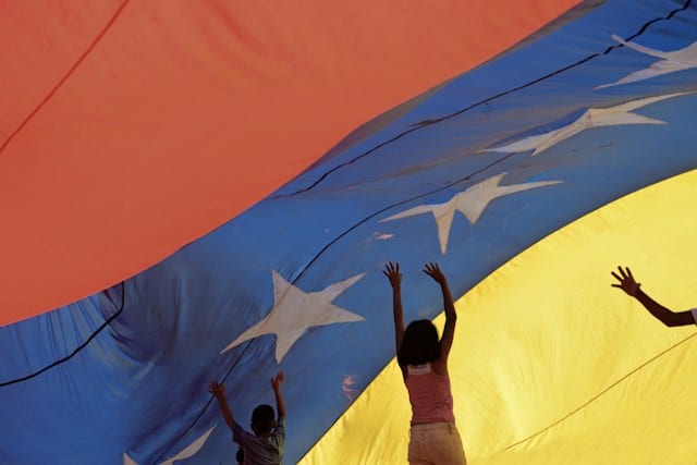 Niños jugando debajo de una bandera venezolana