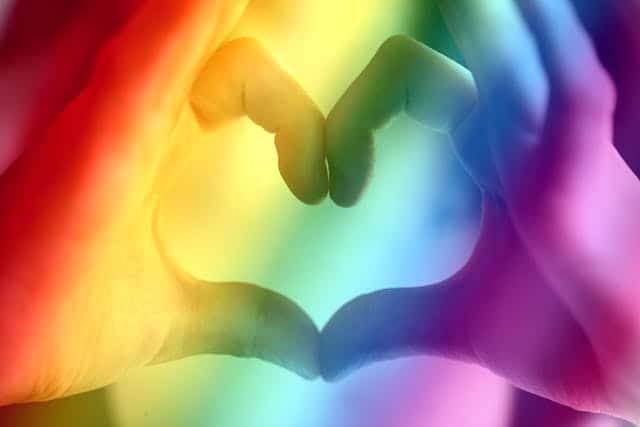 Corazón formado con dos manos con colores de diversidad sexual