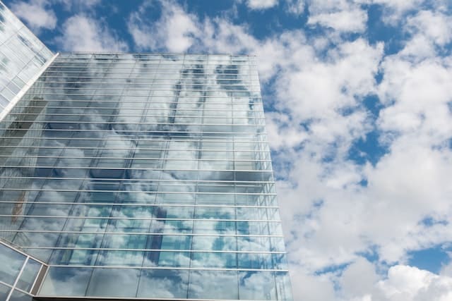 Edificio público lleno de ventanas y un cielo con nubes.
