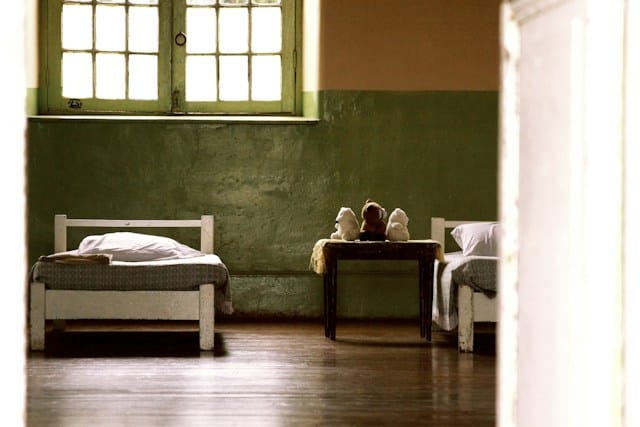 Foto de una habitación humilde para niños con camas y peluches.